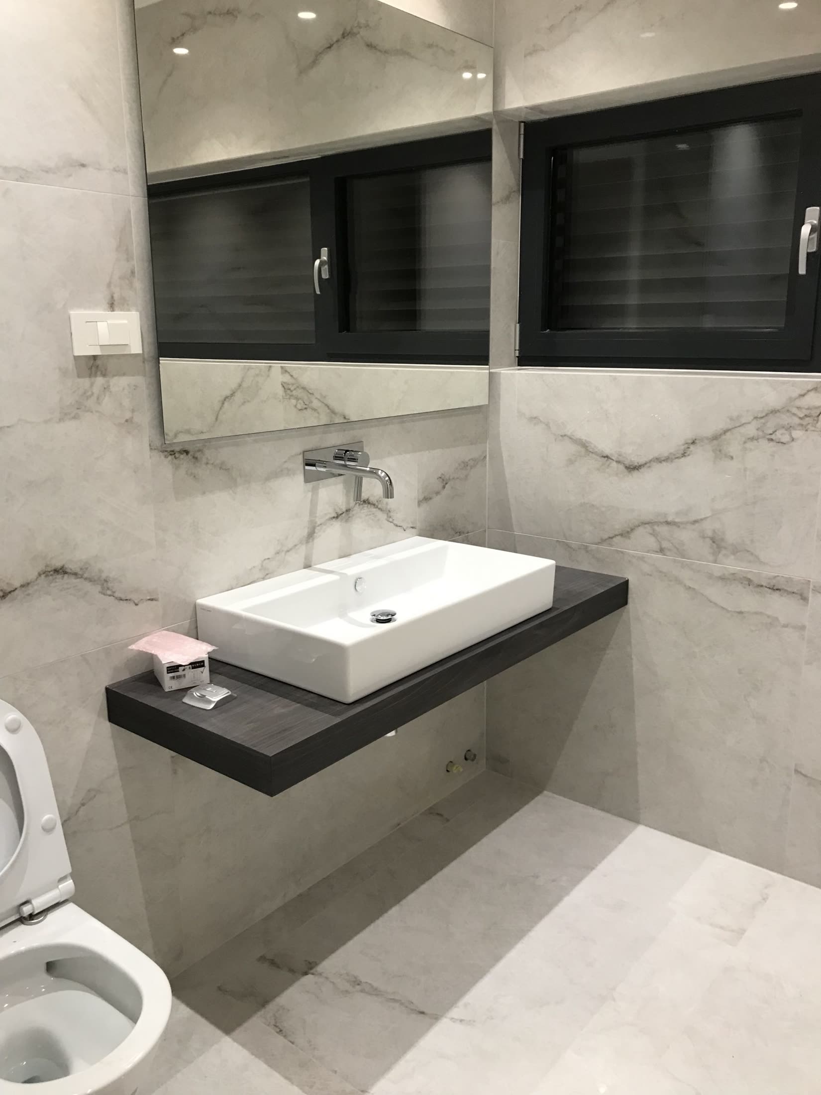 Floating dark wood vanity with marble tiles